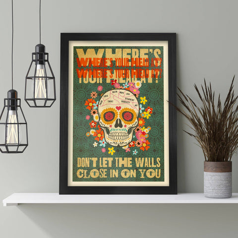 Framed poster with a colorful skull design and text on a shelf with decorative elements.