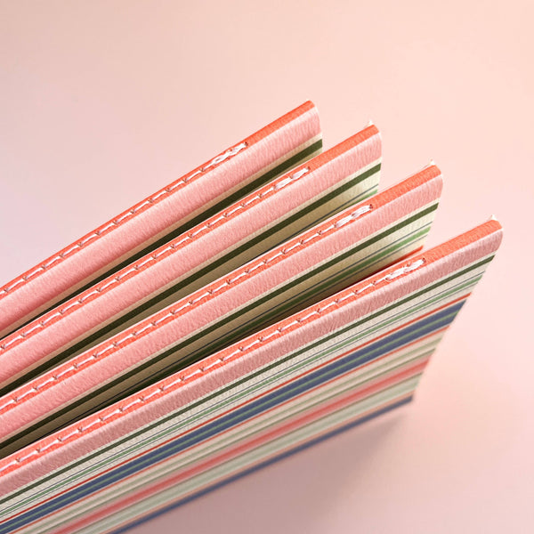 Stack of colorful notebooks with a pink cover on a light pink background