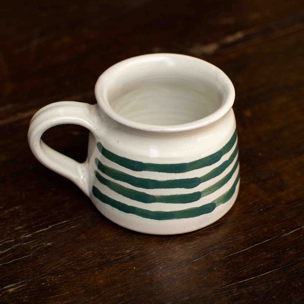 White mug with green stripes on a wooden surface