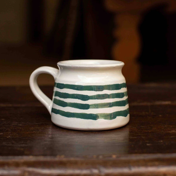 White ceramic mug with green stripes on a wooden surface