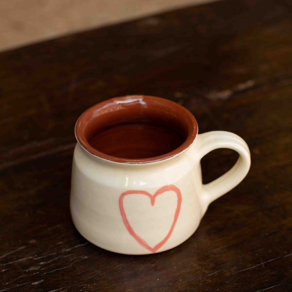 Ceramic mug with a heart design on a wooden surface