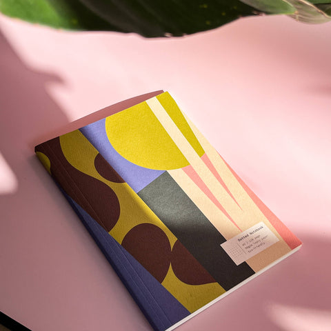 Notebook with colorful abstract design on a pink surface