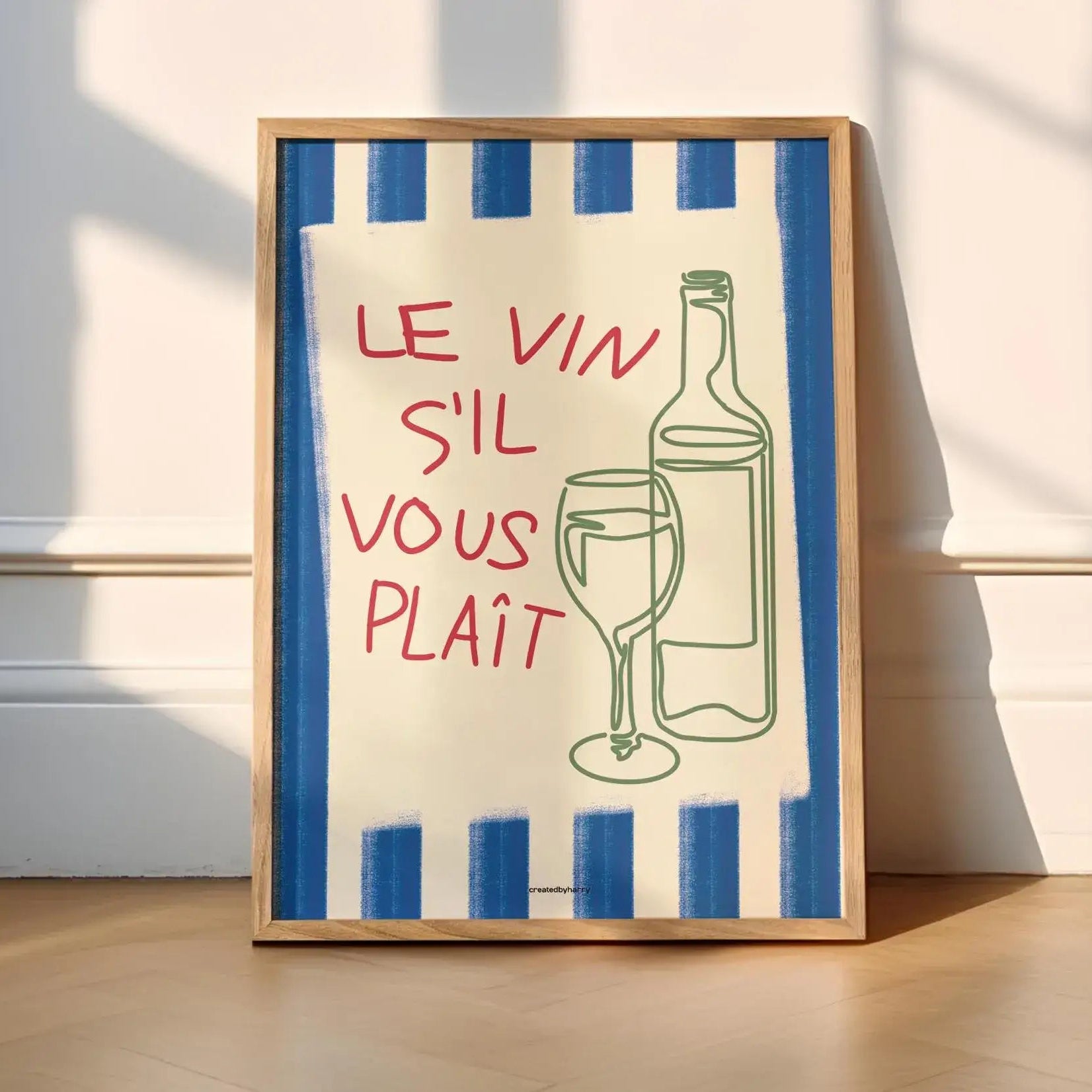 Framed artwork with a blue and white striped border, red text, and a bottle and glass illustration on a light wooden floor.