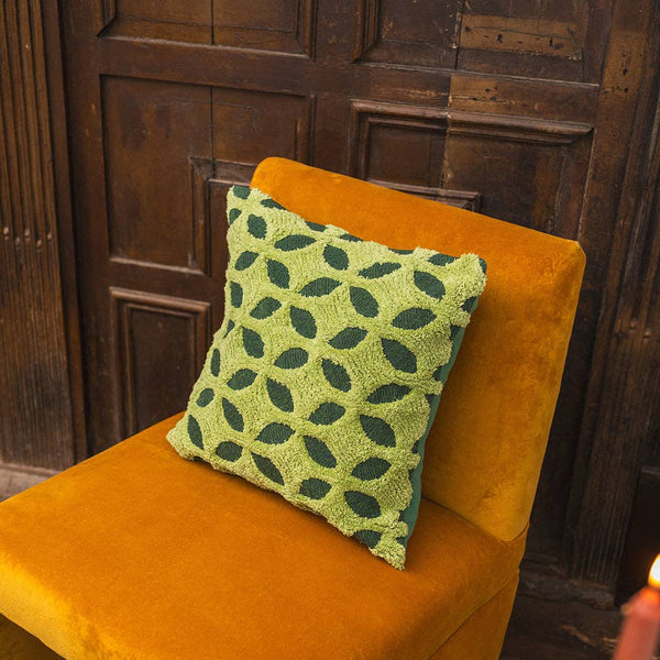 Orange chair with a green patterned pillow against a wooden paneled wall.